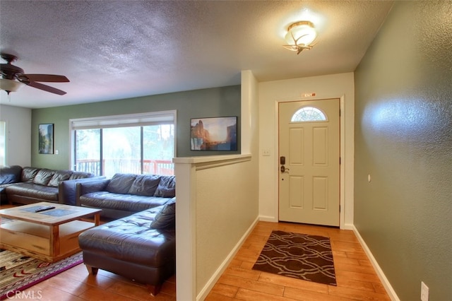 foyer entrance with a textured ceiling, hardwood / wood-style flooring, and ceiling fan