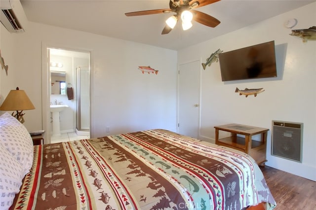 bedroom featuring ensuite bathroom, hardwood / wood-style flooring, ceiling fan, a wall unit AC, and heating unit