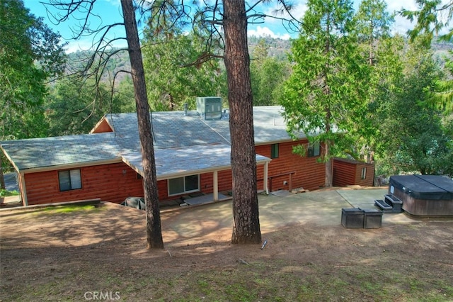 view of property exterior featuring a hot tub and a patio area