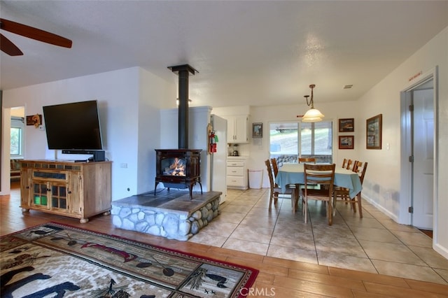 dining area featuring ceiling fan, light hardwood / wood-style floors, and a wood stove