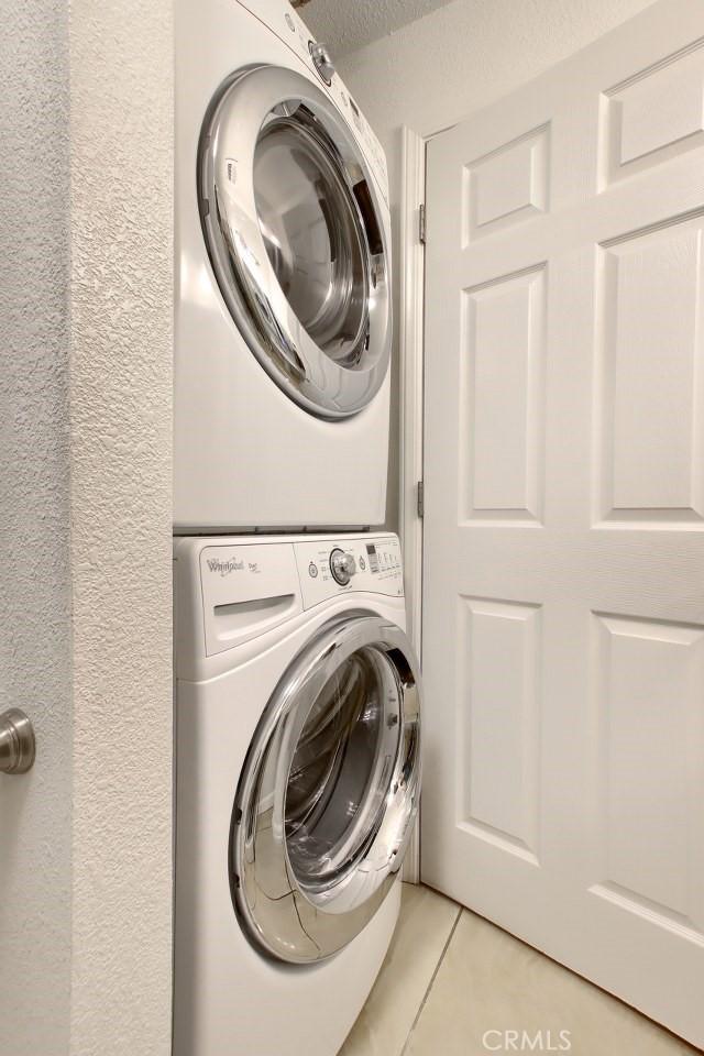 laundry room with stacked washer / drying machine and light tile patterned floors