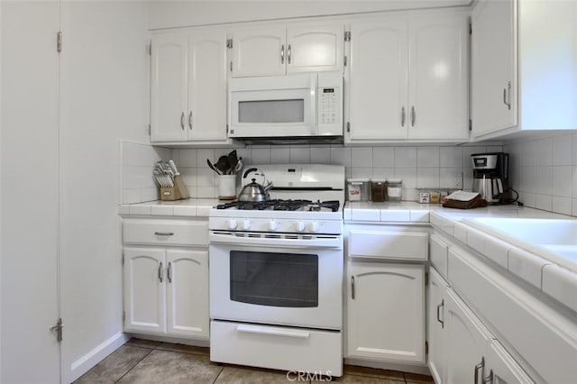 kitchen with white cabinets, decorative backsplash, and white appliances