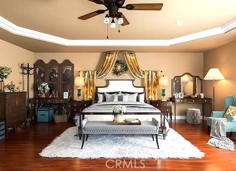 bedroom with a tray ceiling, ceiling fan, and dark wood-type flooring