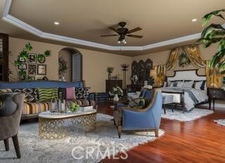 bedroom with a raised ceiling, ceiling fan, and hardwood / wood-style floors