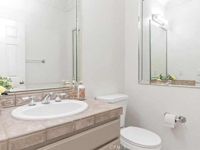 bathroom with toilet, vanity, and ornamental molding