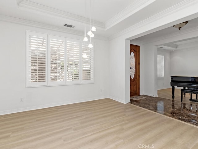 interior space with a raised ceiling, crown molding, and light hardwood / wood-style flooring