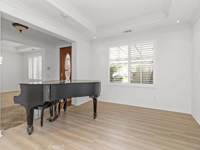 misc room featuring a tray ceiling, ornamental molding, and light wood-type flooring