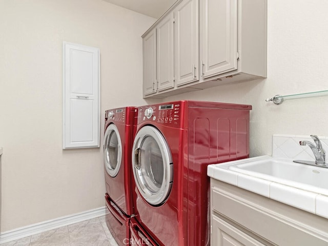 clothes washing area with washer and clothes dryer, light tile patterned floors, cabinets, and sink