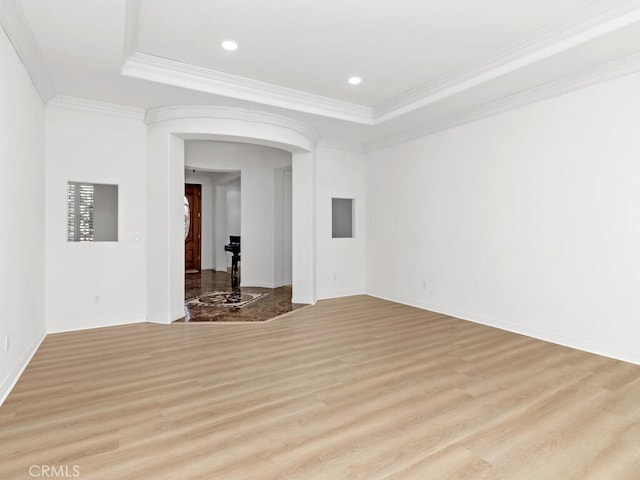 spare room with a tray ceiling, light hardwood / wood-style flooring, and ornamental molding