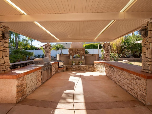 view of patio / terrace with area for grilling and an outdoor stone fireplace