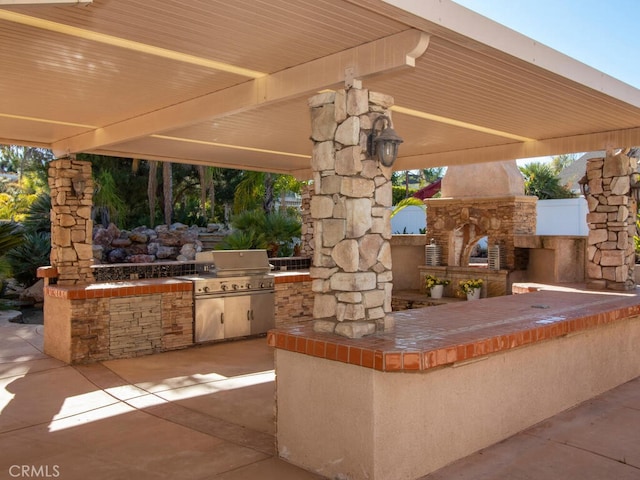 view of patio with exterior fireplace and a grill