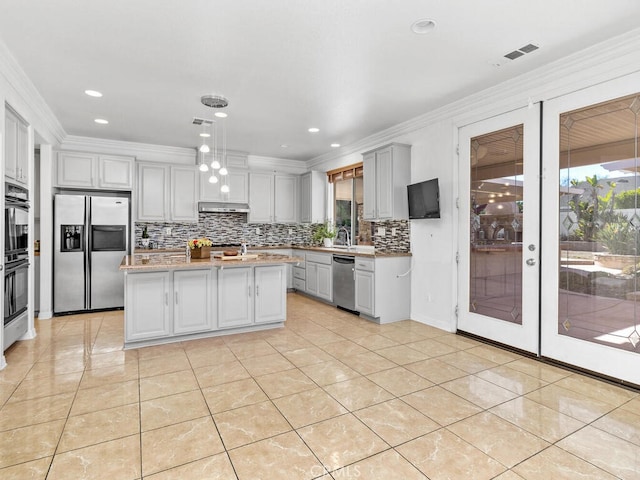 kitchen featuring gray cabinetry, ornamental molding, light tile patterned floors, a kitchen island, and stainless steel appliances