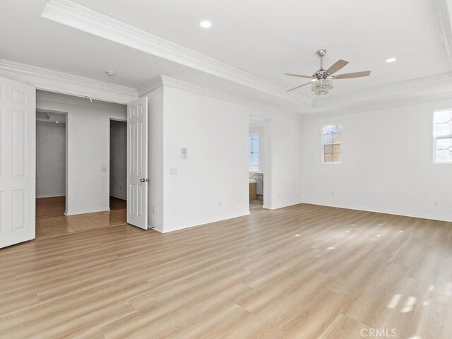 spare room featuring ceiling fan, a raised ceiling, light wood-type flooring, and ornamental molding