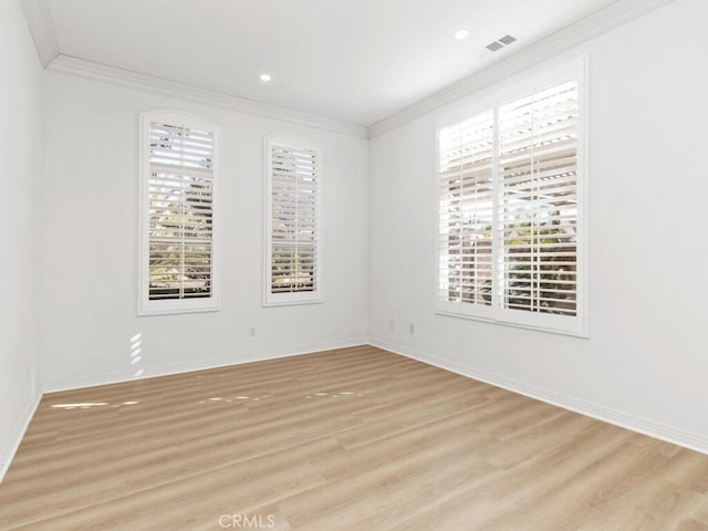 spare room with light hardwood / wood-style flooring, a wealth of natural light, and ornamental molding