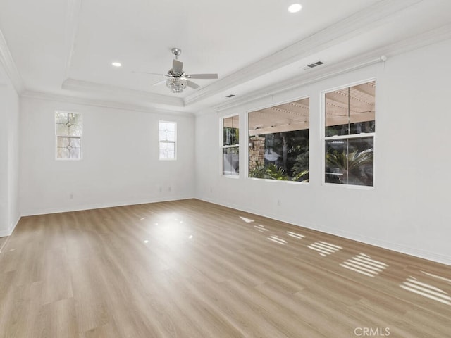 empty room with light hardwood / wood-style flooring, a raised ceiling, ceiling fan, and ornamental molding