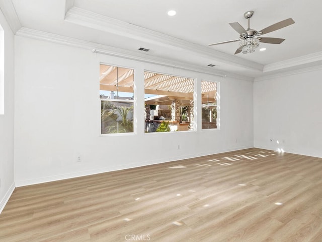 spare room featuring a raised ceiling, crown molding, ceiling fan, and light hardwood / wood-style floors