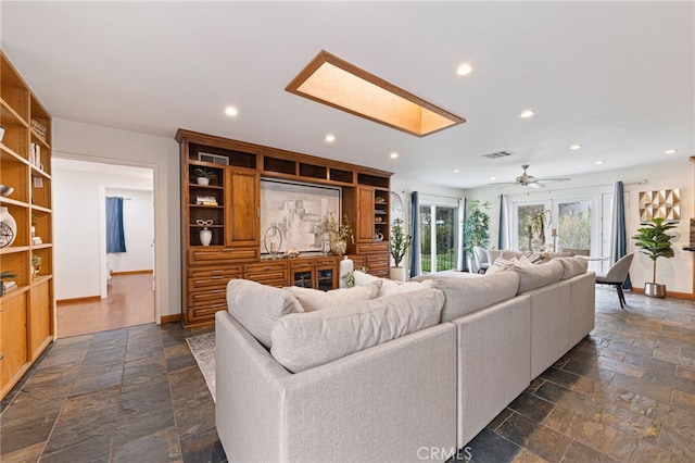 living room with ceiling fan and a skylight