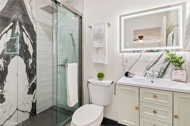 bathroom with an enclosed shower, vanity, toilet, and ceiling fan