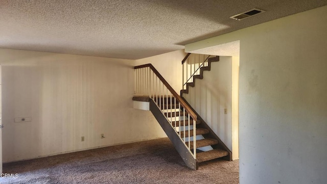 staircase featuring carpet and a textured ceiling