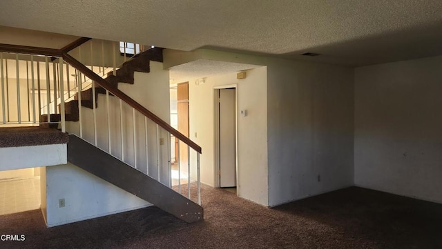 stairway with carpet flooring and a textured ceiling