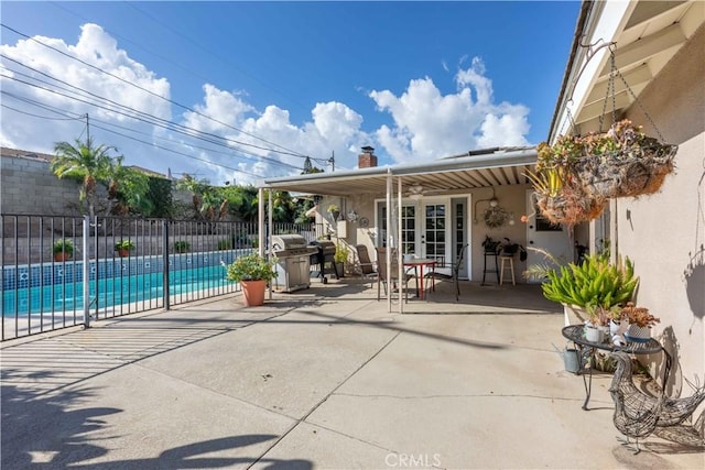 view of patio / terrace featuring a fenced in pool, a grill, and french doors