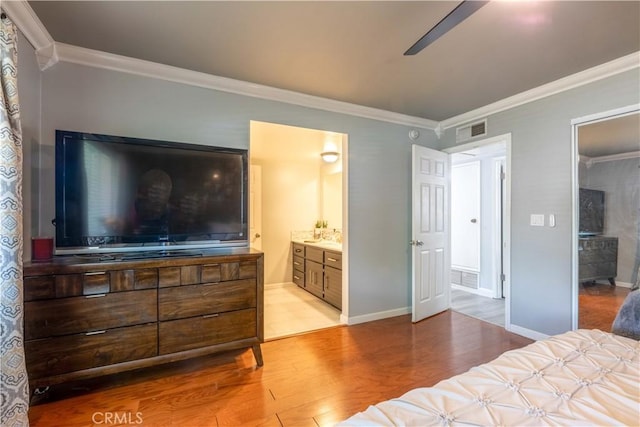 bedroom featuring ensuite bathroom, light wood-type flooring, crown molding, and ceiling fan