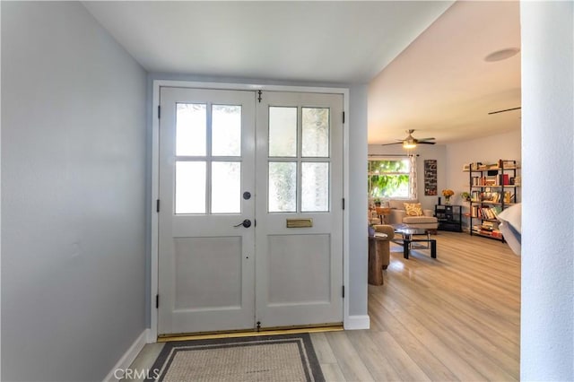 doorway with light wood-type flooring, ceiling fan, and french doors