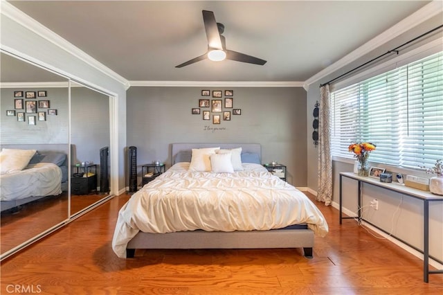 bedroom with ceiling fan, a closet, ornamental molding, and wood-type flooring