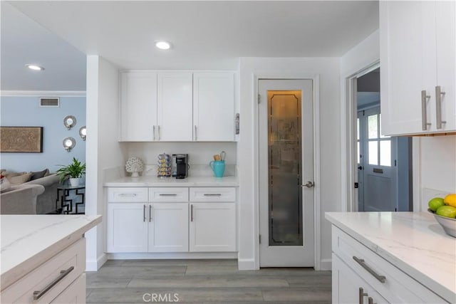 kitchen with light stone countertops, white cabinetry, and light wood-type flooring