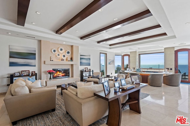 tiled living room featuring beam ceiling, a water view, and a tray ceiling