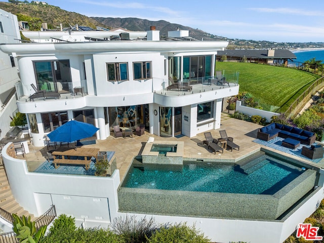 rear view of property featuring a patio area, an outdoor hangout area, and a pool with hot tub