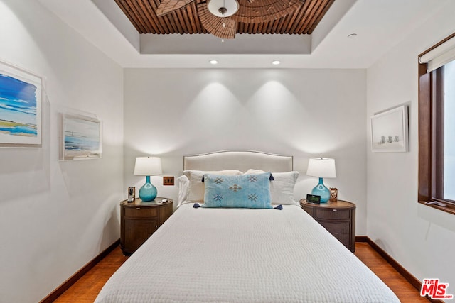 bedroom with a raised ceiling and dark hardwood / wood-style floors