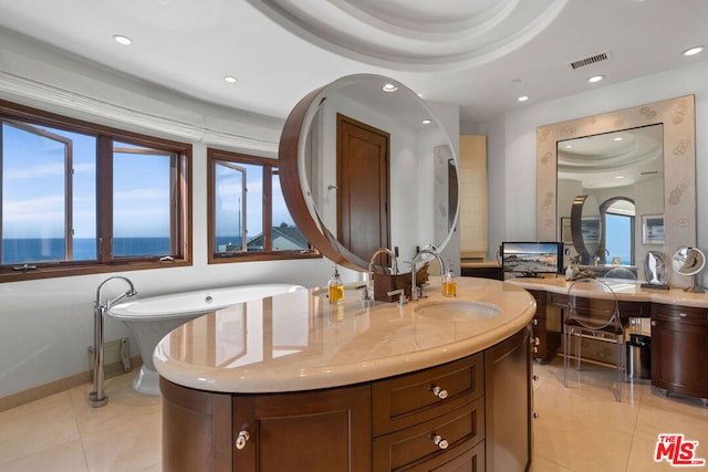 bathroom featuring a washtub, a raised ceiling, tile patterned flooring, a water view, and vanity