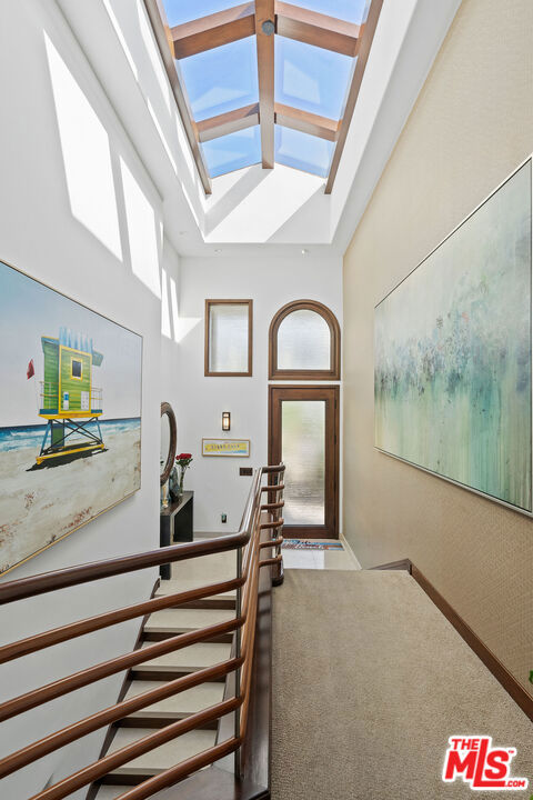 stairs with carpet, a skylight, and high vaulted ceiling