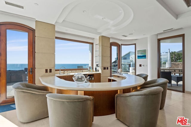 dining area featuring a water view, light tile patterned floors, sink, and a wealth of natural light