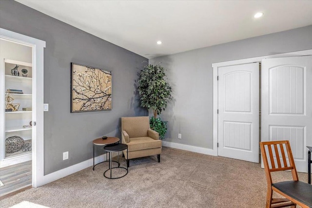 living area featuring light carpet and built in shelves