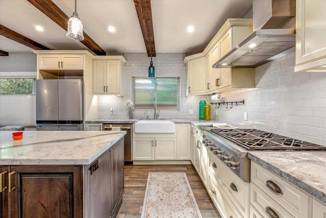 kitchen with decorative light fixtures, wall chimney range hood, stainless steel appliances, hardwood / wood-style flooring, and beam ceiling