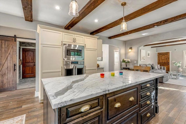 kitchen with a barn door, dark brown cabinets, stainless steel appliances, and pendant lighting