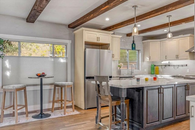 kitchen with light stone countertops, a kitchen bar, stainless steel fridge, and a center island