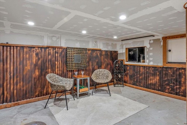 sitting room featuring concrete floors and wooden walls