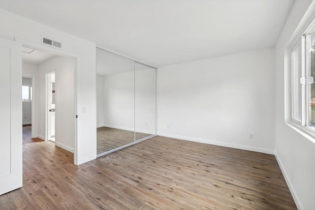 unfurnished bedroom featuring a closet and hardwood / wood-style flooring