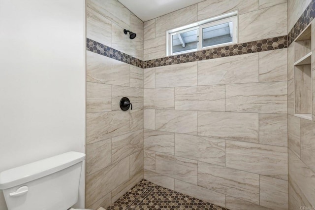 bathroom featuring tiled shower and toilet