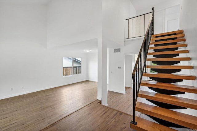 staircase featuring hardwood / wood-style floors and a high ceiling