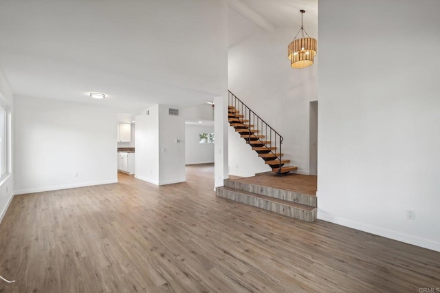 unfurnished living room with beamed ceiling, high vaulted ceiling, and wood-type flooring