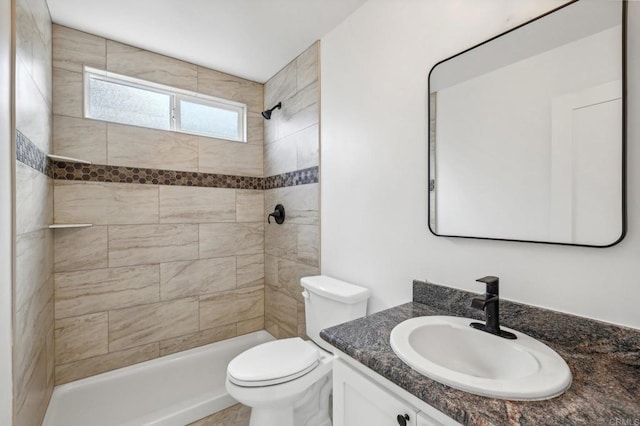 bathroom with vanity, toilet, and tiled shower