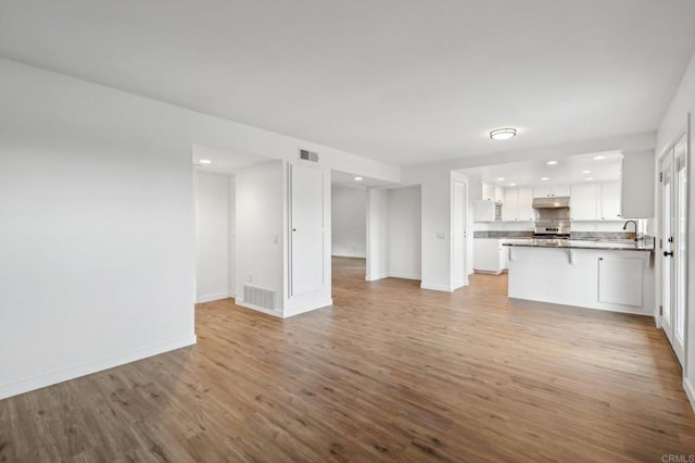 unfurnished living room featuring light hardwood / wood-style floors and sink