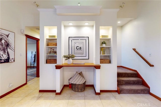 corridor with built in shelves, light tile patterned floors, and ornamental molding