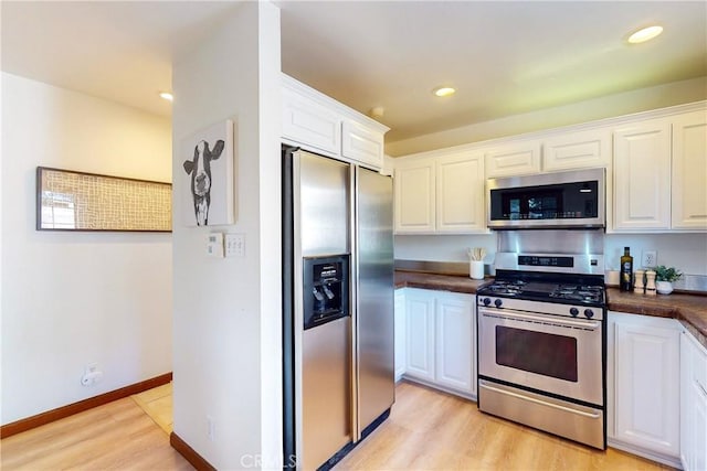 kitchen with white cabinets, light wood-type flooring, and stainless steel appliances