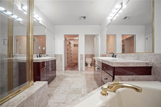 bathroom with vanity, toilet, and tile walls