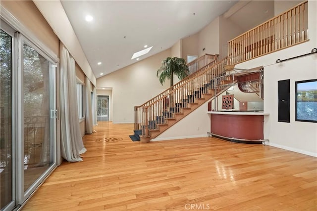 interior space featuring a skylight, light hardwood / wood-style flooring, and high vaulted ceiling